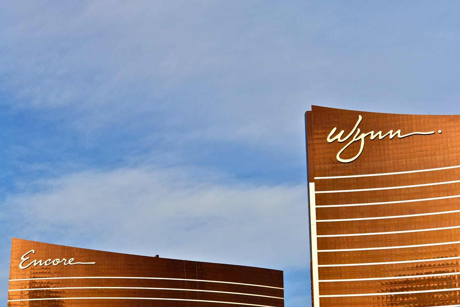 Bronze Wynn and Encore resort towers against a blue sky on the North Las Vegas Strip